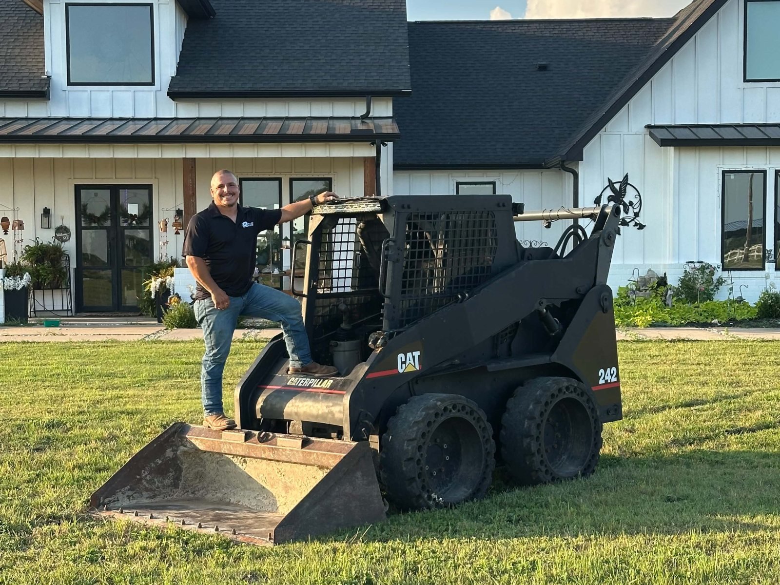 Owner of Berglund Services with his Caterpillar skid steer in front of a finished North Texas home